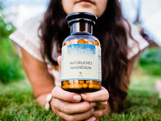 Woman holding bottle of natural vegan magnesium supplement outdoors