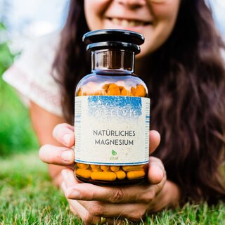 Woman presenting vegan magnesium vitamins on grass for healthy living